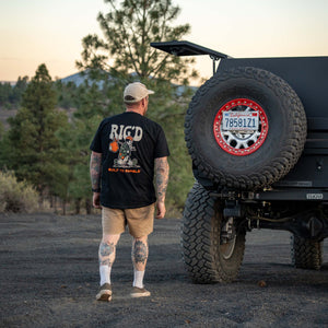Man walking towards a large off-road vehicle with a spare tire cover featuring a logo.