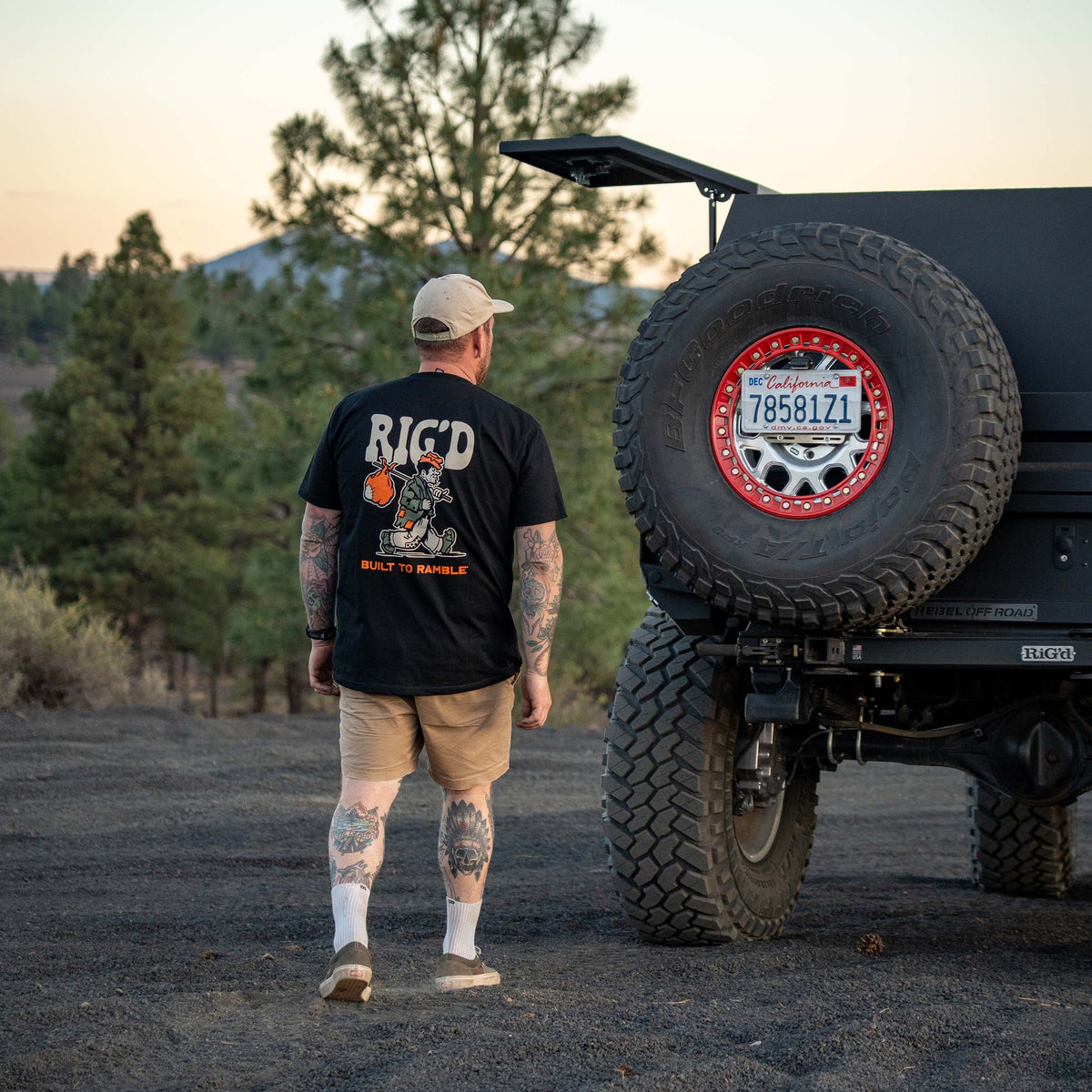 Man walking towards a large off-road vehicle with a spare tire cover featuring a logo.